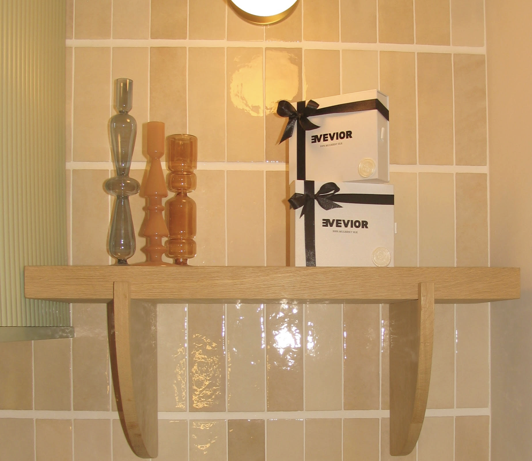 Wooden shelf with decorative items and Evevior boxes against a tiled wall