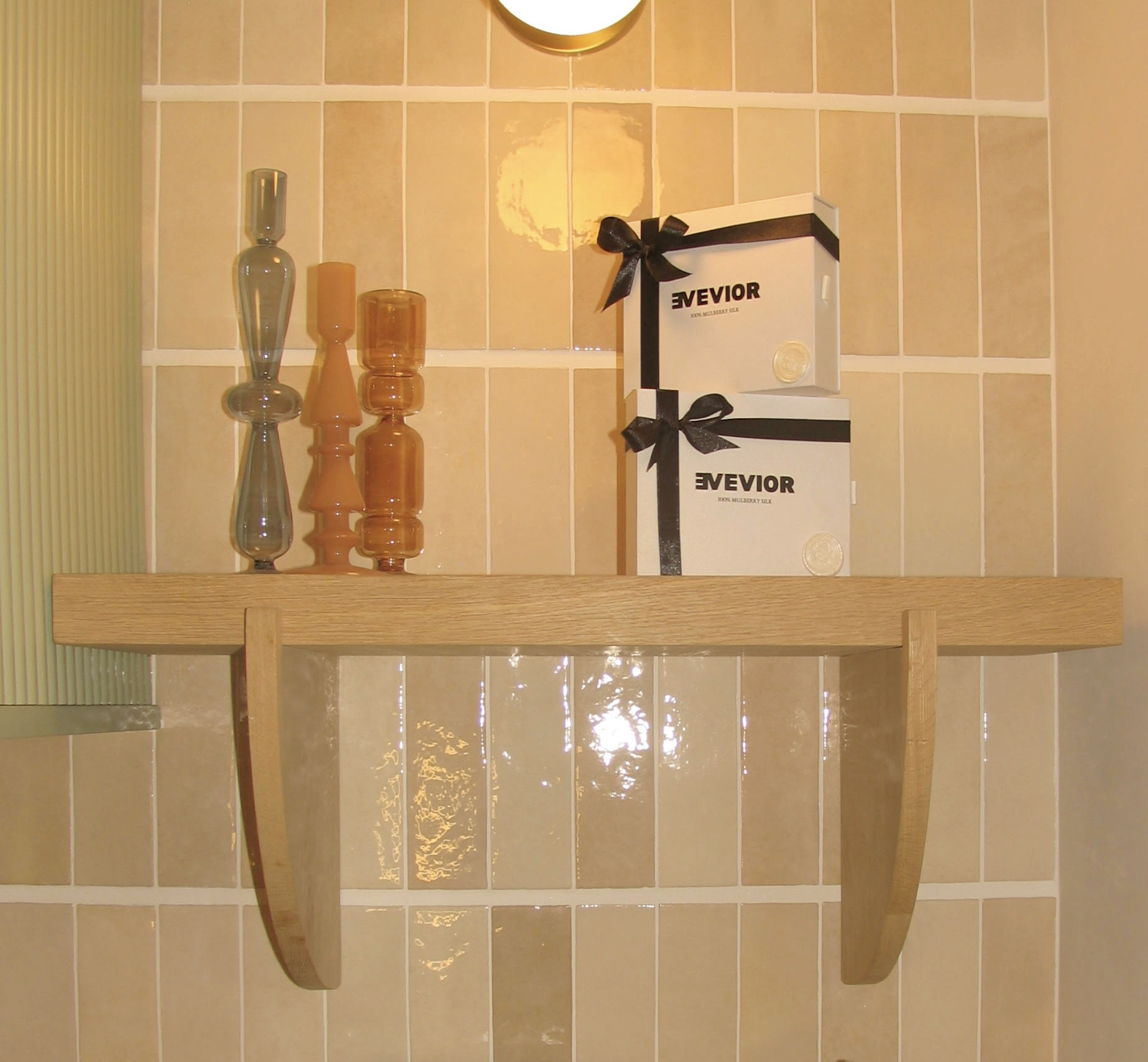 Two Evevior packaging boxes stacked on a wooden shelf with decorative glass objects.