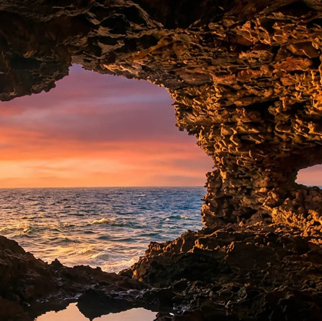 Sunset viewed from inside a rocky cave at Animal Flower Cave with ocean view.