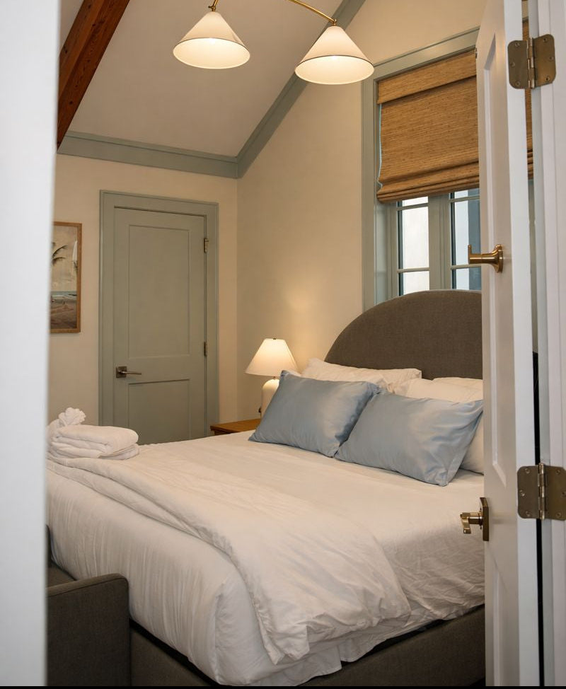 Cozy bedroom with a neatly made bed and two blue silk pillows.