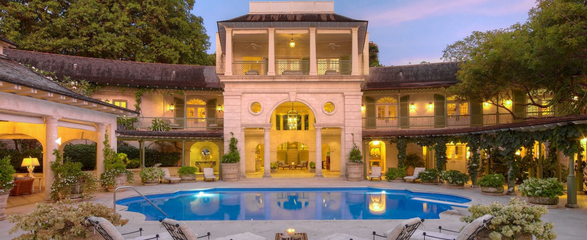 Front view of a three-story villa with a swimming pool and lounge chairs.