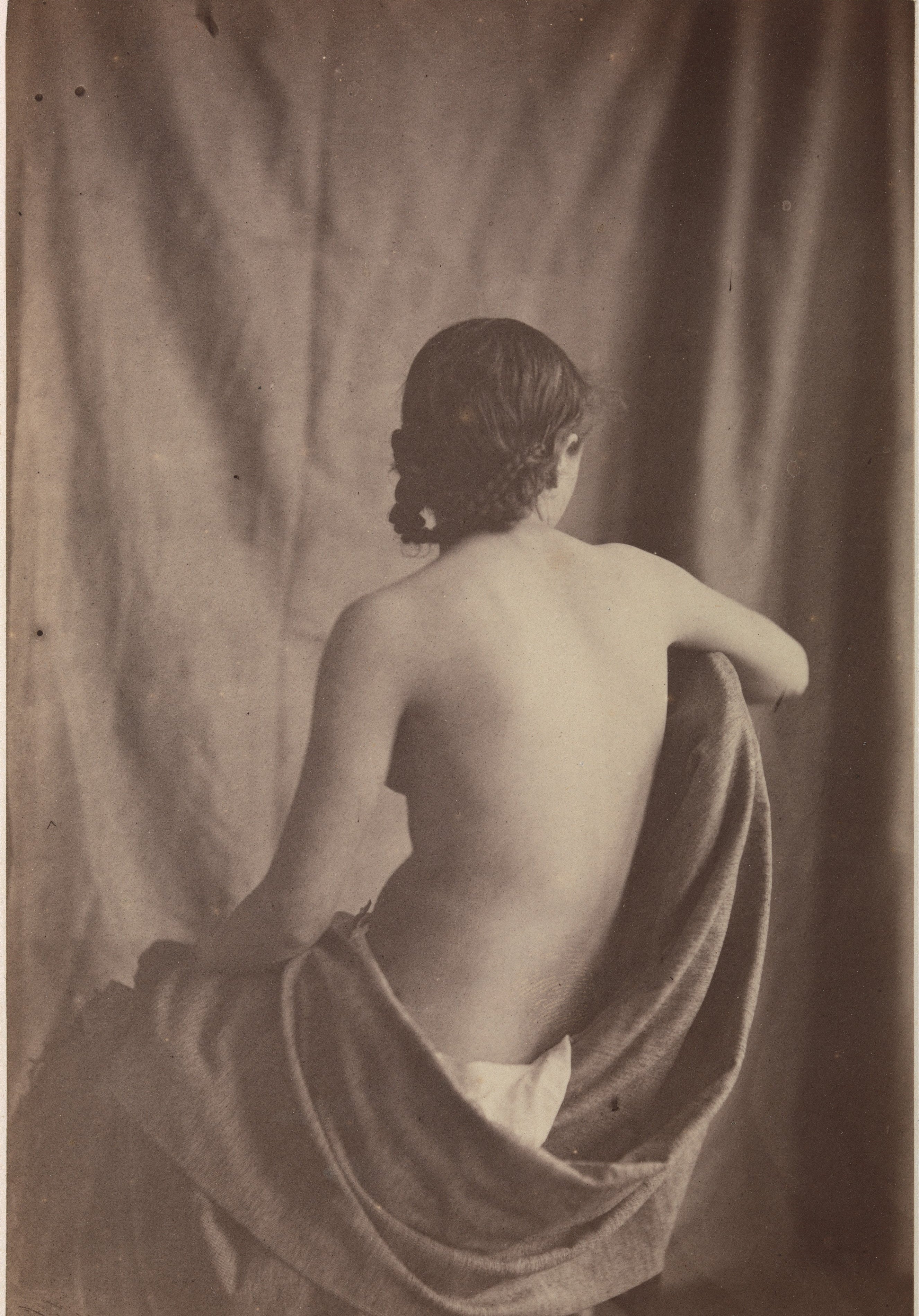 Nude figure draped with fabric against a plain background