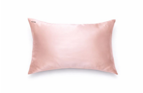 Blush pink silk pillowcase with small black embroidered logo in the top right corner.